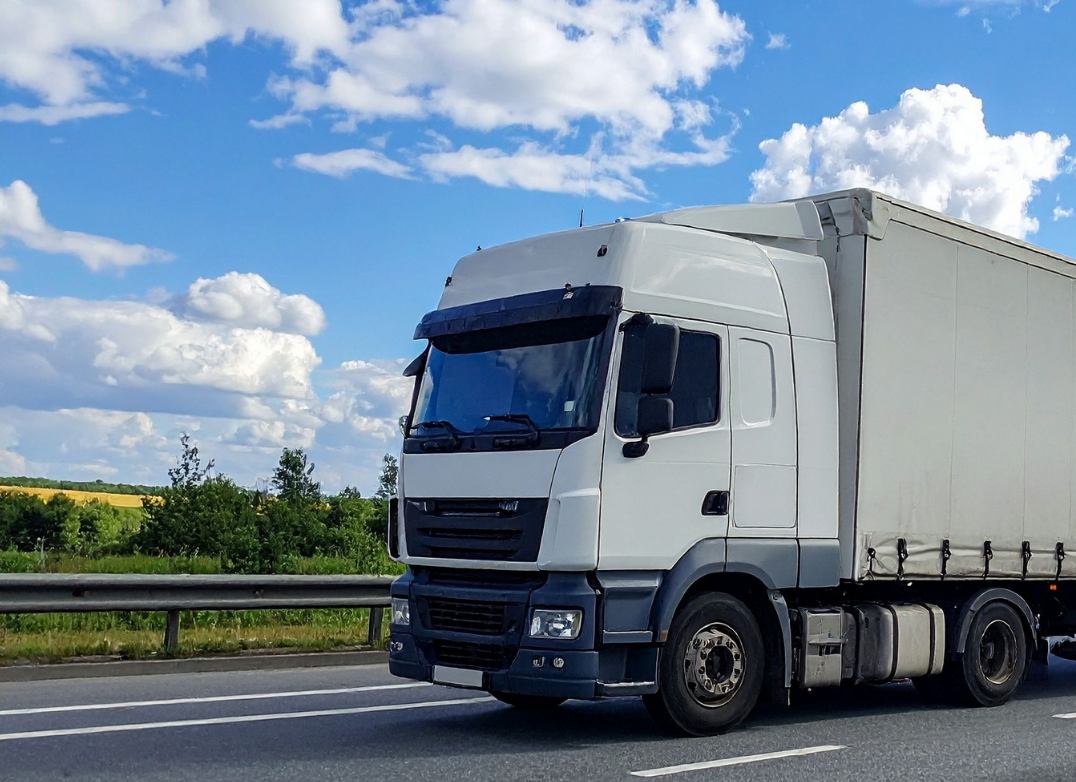 Truck on the highway past green fields